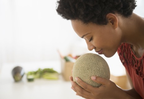 Black woman smelling cantaloupe