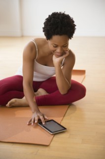 Black woman using digital tablet on yoga mat