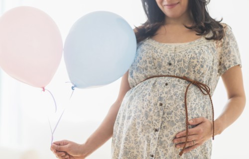 Pregnant Hispanic woman carrying balloon