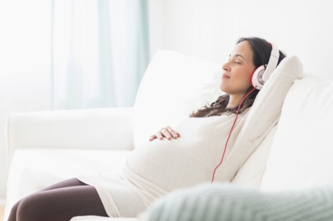 Pregnant Hispanic woman listening to headphones