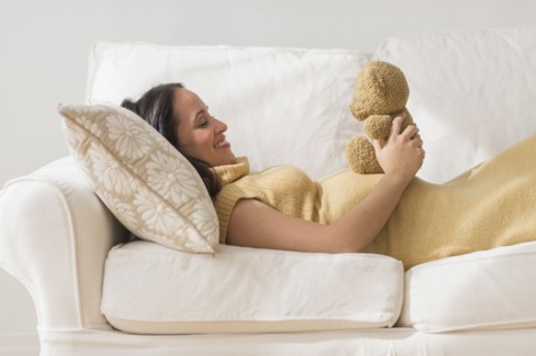 Pregnant Hispanic woman admiring teddy bear