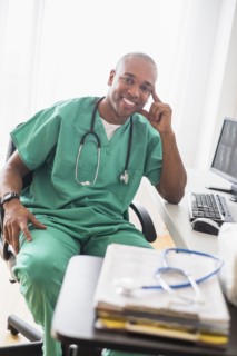 Black doctor smiling at computer in office