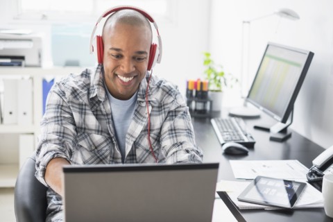 Black businessman listening to headphones in office