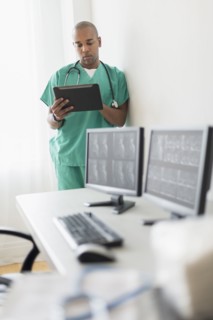 Black doctor using digital tablet in office