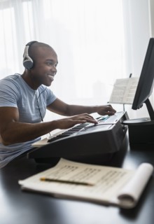 Black musician writing music on computer