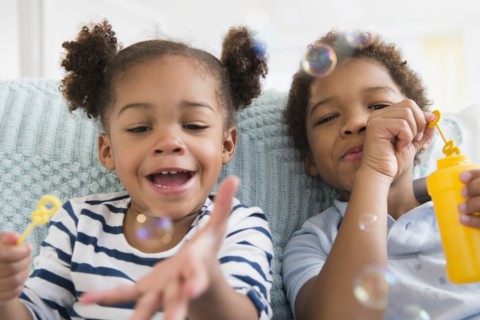 Black children blowing bubbles together