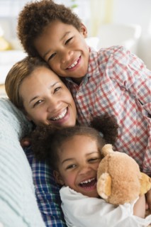 Black mother and children smiling on sofa