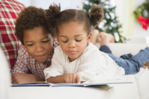 Black children reading together on sofa