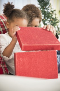 Black children opening Christmas gift on sofa