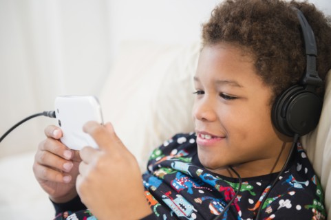 Black boy listening to headphones on sofa