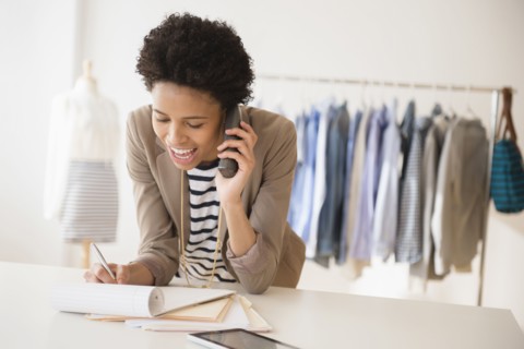Black dressmaker talking on phone in studio