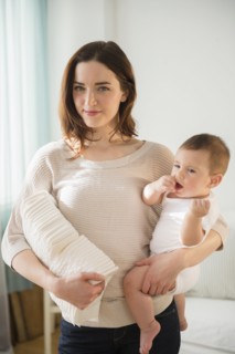 Mother holding baby and stack of diapers