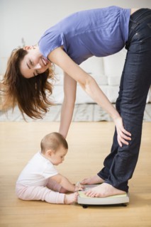 Mother with new baby standing on scale