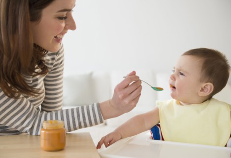 Mother feeding baby in high chair