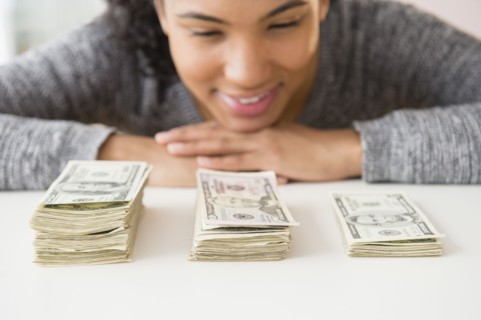 Mixed race woman counting stacks of money
