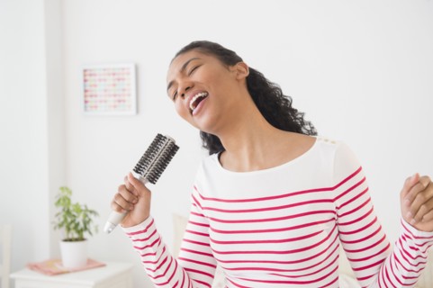 Mixed race woman singing into hairbrush