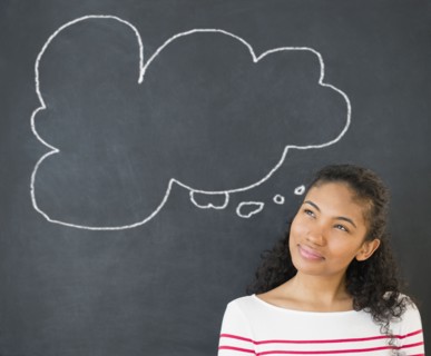 Mixed race woman under thought bubble on chalkboard
