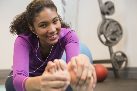 Mixed race woman stretching in gym