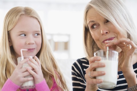 Senior Caucasian woman and granddaughter drinking milk