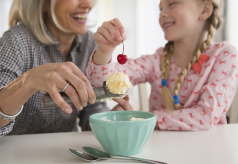 Senior Caucasian woman and granddaughter making ice cream sundae