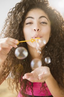 Mixed race woman blowing bubbles