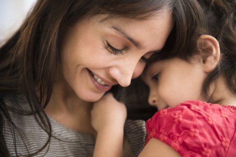 Hispanic girl whispering in mother's ear