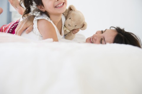 Hispanic mother and daughter relaxing on bed