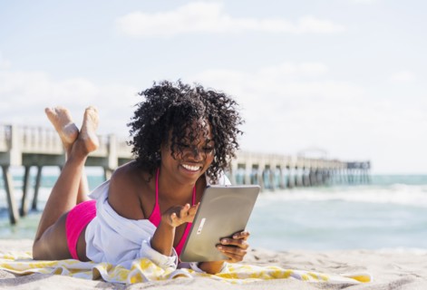 African American woman using digital tablet on beach