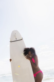 African American woman holding surfboard on beach