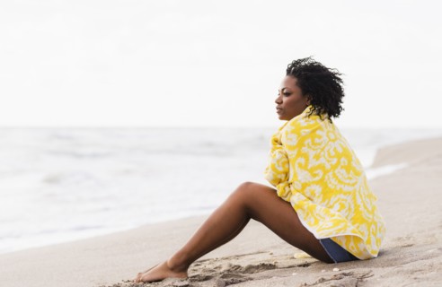 African American woman wrapped in towel on beach