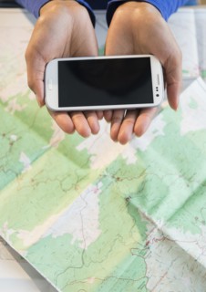 Mixed race woman holding cell phone over map
