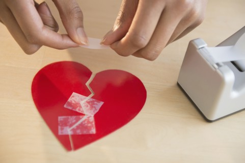 Mixed race woman taking broken paper heart