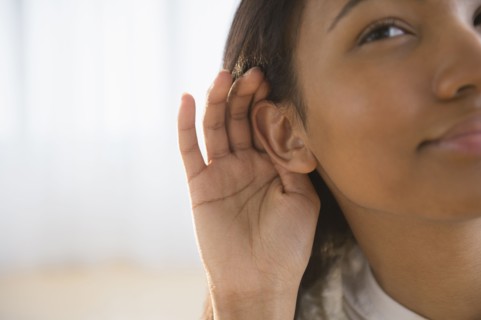 Mixed race woman cupping her ear
