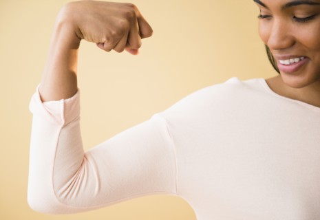 Mixed race woman flexing her muscles