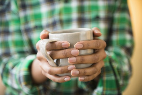 Mixed race woman holding cup of coffee