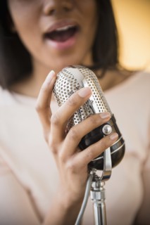 Mixed race woman singing into vintage microphone