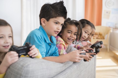 Children playing video games on sofa