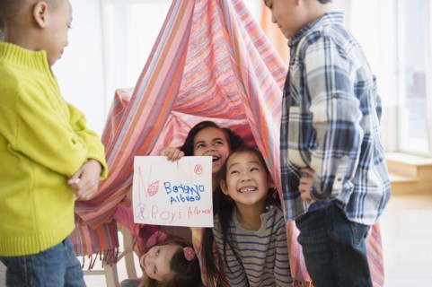 Girls holding No boys Allowed sign in living room