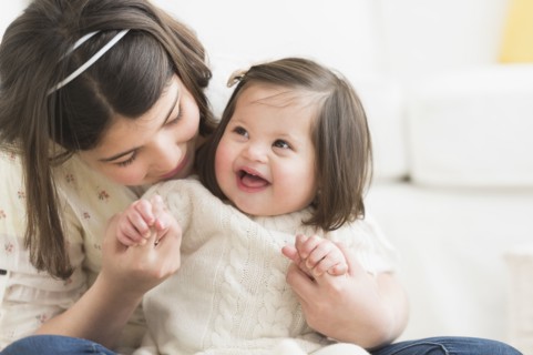 Hispanic girl holding toddler sister in living room