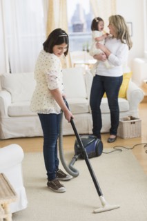 Hispanic girl vacuuming living room