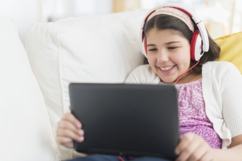 Hispanic girl using digital tablet on sofa