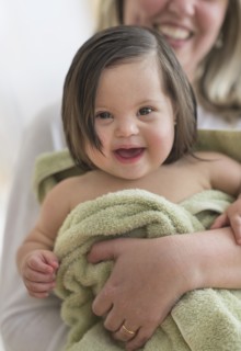 Hispanic mother drying toddler daughter after bath