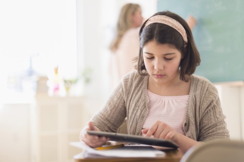 Hispanic girl using digital tablet in classroom