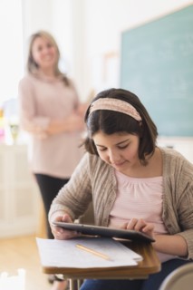 Hispanic girl using digital tablet in classroom