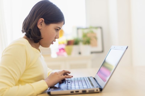 Hispanic girl using laptop at desk