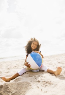 Mixed race girl playing with ball on beach