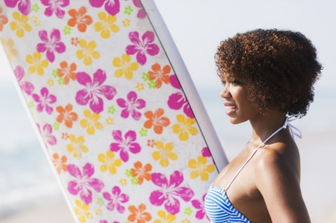 Woman carrying surfboard on beach
