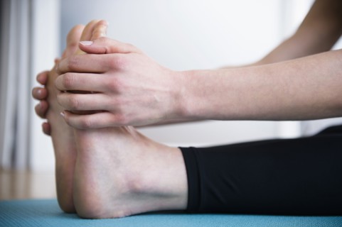 Caucasian woman stretching legs on yoga mat