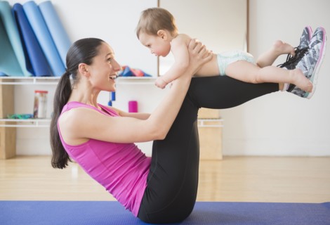Caucasian woman holding baby on yoga mat