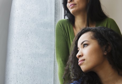 Mother and daughter daydreaming at window